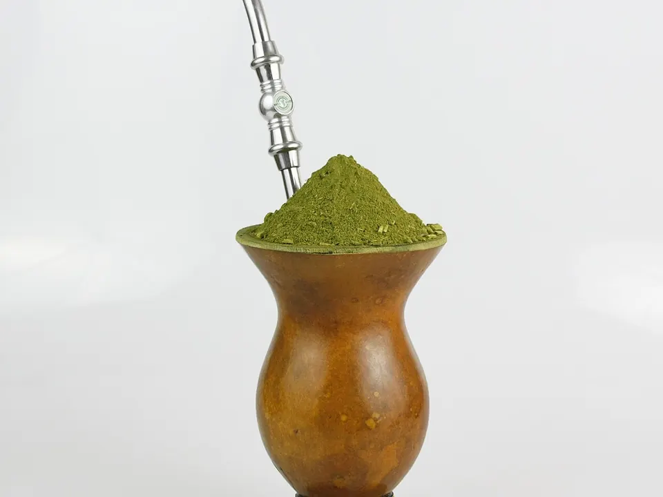 Cuia de chimarrão com bomba de metal e erva-mate ao lado de uma térmica